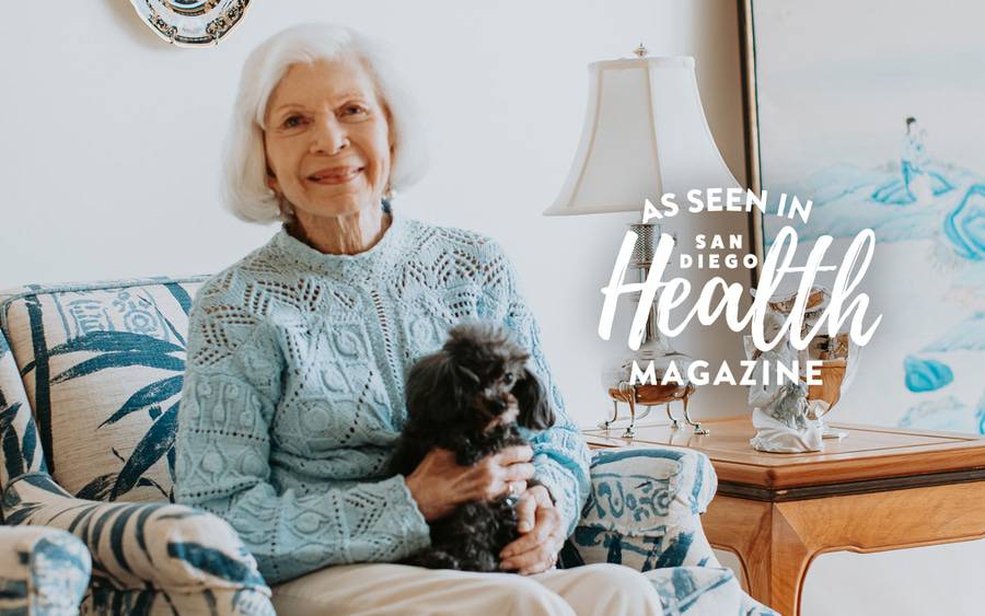 Barbara Smith sits on a chair holding her small dog. San Diego Health Magazine