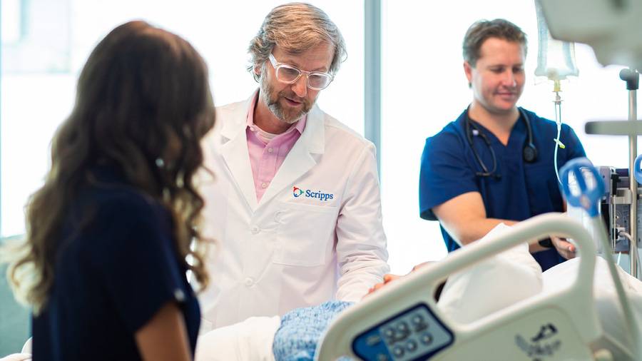 Scripps physician, Dr. Kevin Fussel speaking with a patient while two nurses continue monitoring them.