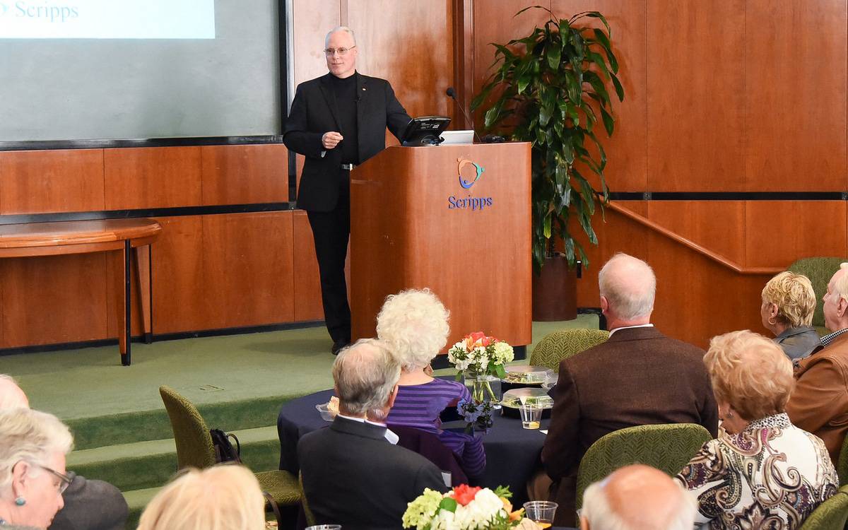 Chris Van Gorder, President and CEO of Scripps Health, stands at the podium as he talks to President's Council supporters during a luncheon.