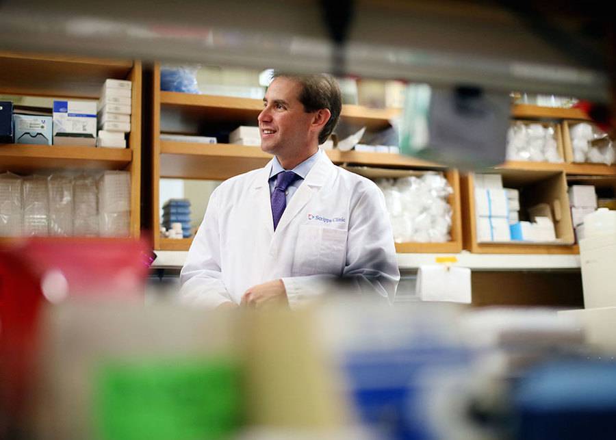 A Scripps MD Anderson Cancer Center oncologist amidst shelves of hospital equipment used for patients and clinical research.