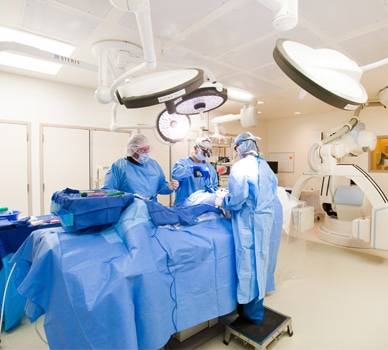Cardiologists perform heart surgery on a patient.