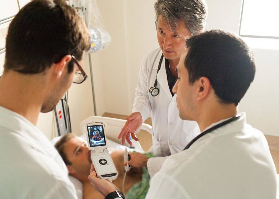 A group of physicians huddling around an ultrasound device