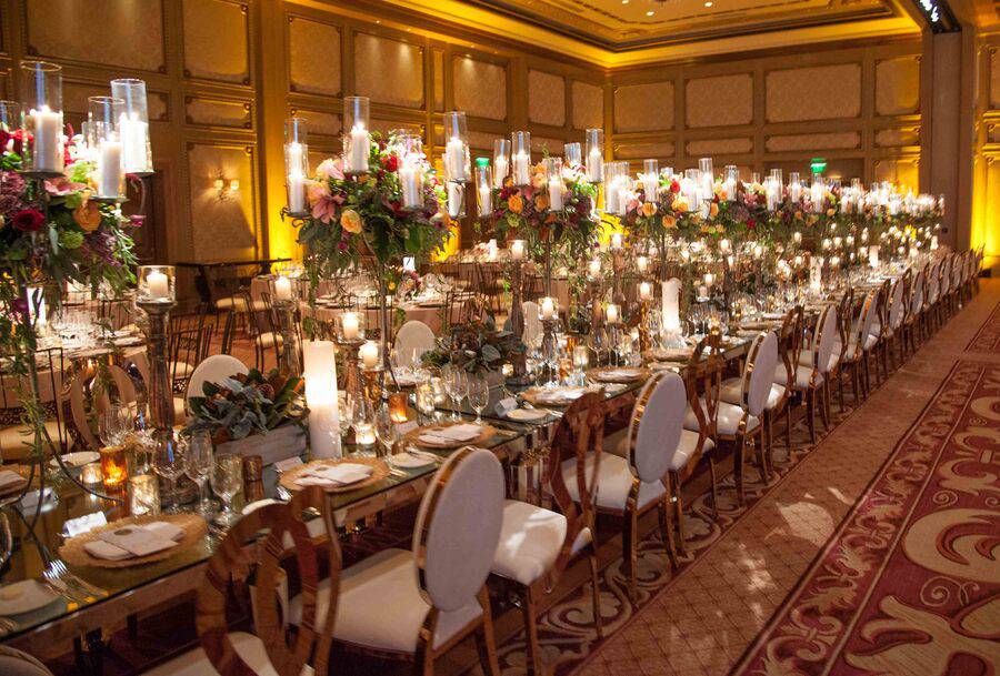 A ballroom with a long table set up for dinner event.