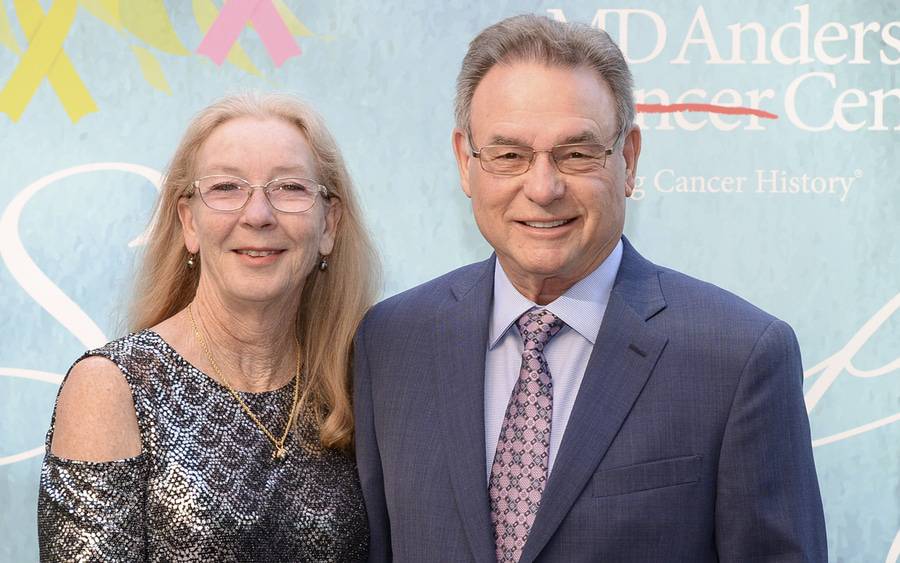 Fred and Lynda Allen stand in front of a banner for Scripps MD Anderson Cancer Center at a fundraising event.