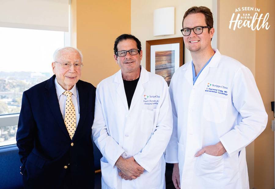 Two doctors in white lab coats standing next to a patient