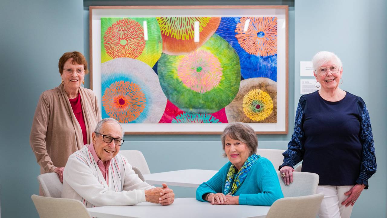 Members of the La Costa Glen Friendship Committee at Scripps Memorial Hospital Encinitas pictured with a framed colorful work of art that is displayed in the new Lusardi Tower.