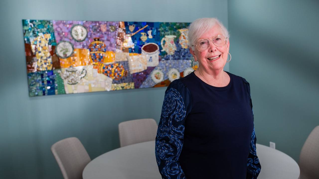 Ruby Edman, a La Costa Glen Friendship Committee member, pictured with a colorful mosaic piece depicting a deconstructed tea party at the Lusardi Tower at Scripps Memorial Hospital Encinitas.
