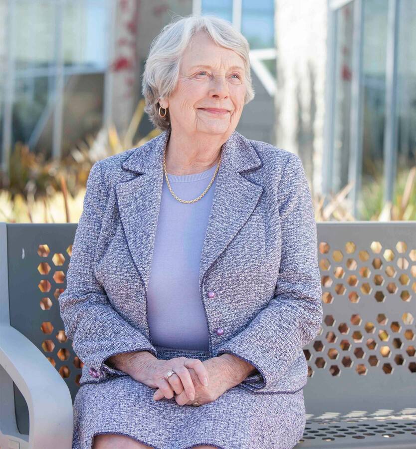 Jean Anderson sits on a bench outdoors.