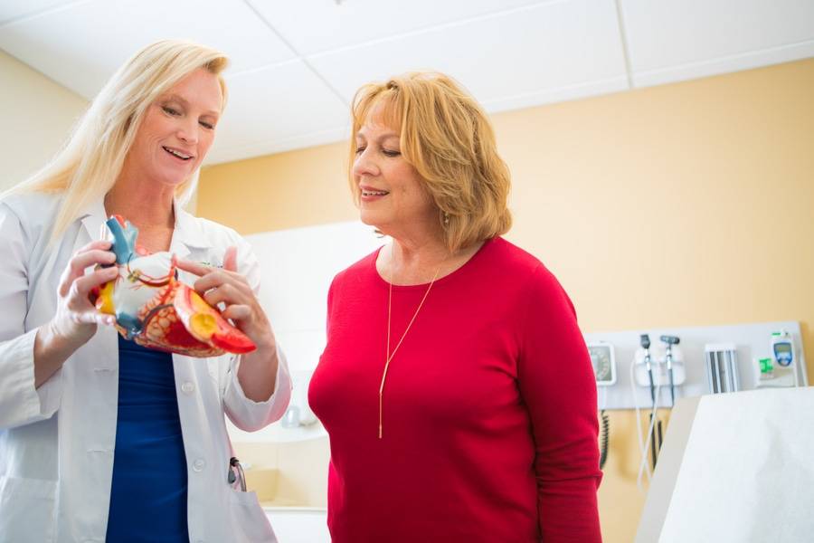 A Scripps doctor uses a model of a heart to explain heart disease to a woman patient.