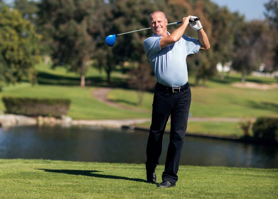 After successful cancer treatment, Steve Young smiles after hitting the ball on the golf course.