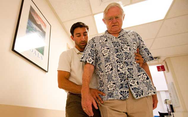 A therapist helps a stroke patient begin to walk.