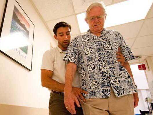 A therapist helps a stroke patient begin to walk.